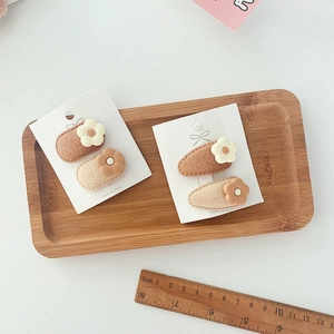 Detail of floral drop BB hair clips for kids on card, cream and brown felt finish