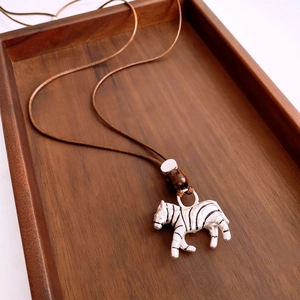 Detailed view of zebra striped pendant on brown woven rope with wooden beads