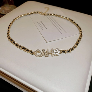 Close-up of gold-plated chain necklace with pearl letters and white camellia flower