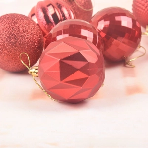 Close-up of red Christmas baubles with glitter, matte, and faceted textures with gold strings