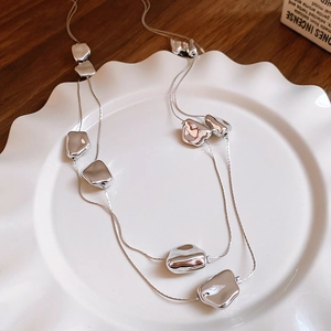 Dettaglio di perle metalliche geometriche irregolari argentate sulla collana