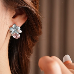 Détail porté de boucles d'oreilles vintage fleurs bleues avec cristal rose et perles
