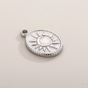 Close-up of a silver stainless steel oval pendant with embossed sun and moon star patterns
