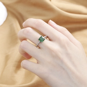 Silver ring featuring square emerald stone and micro-pave zircons on model finger