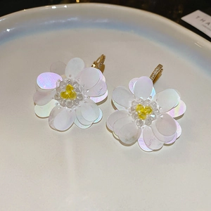 Detail of flower earrings with white iridescent sequins and gold zircon hooks