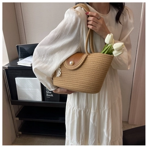Detailed view of handmade woven straw tote bag with pearl buckle and lace charm accessory