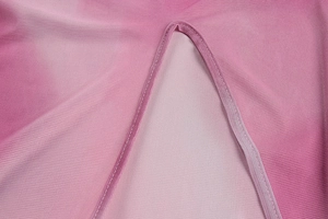 Detail of pink gradient tie-dye fabric with fine horizontal knit texture and curved seam