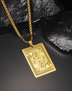 Macro shot of gold stainless steel King of Hearts poker card pendant on dark rock