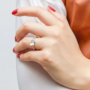 Detail of 925 sterling silver bow ring with zircon on model's hand with red nails