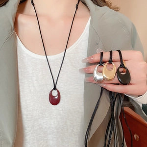 Détail de pendentifs ovales ajourés en couleurs rouge, doré, argent et noir