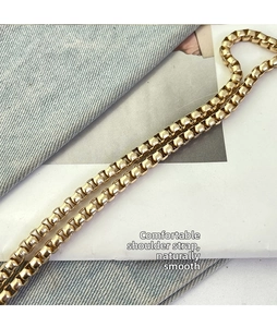 Detail of a warm golden square link chain strap for crossbody bags with metallic finish