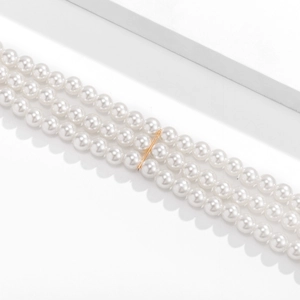 Detailed close-up of triple-layered faux pearl necklace with gold metal spacers