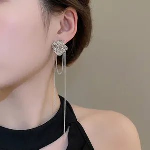 Elegant silver rose flower tassel earrings on female model with long dangling chain detail