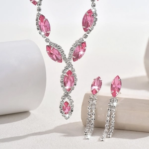 Macro detail of teardrop pink crystal necklace and tassel earrings on white display