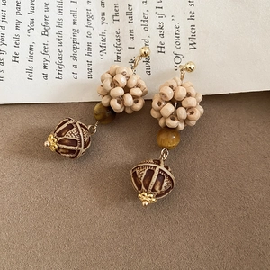 Detailed close-up of tiger eye stone and wooden beaded earrings on a vintage book