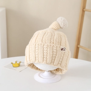 Beige knit infant beanie with a white pom-pom and cute elephant patch detail
