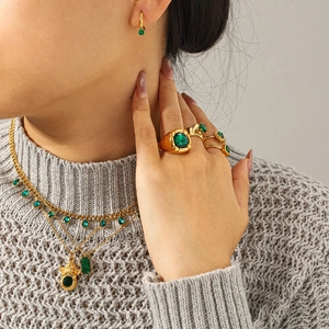Golden jewelry set with green zircon necklace, earrings and rings on a model