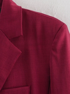 Detail of burgundy blazer notch lapel and shoulder tailoring with smooth fabric texture