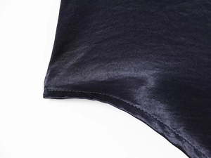 Macro shot of dark blue satin fabric with detailed hem stitching and silky texture