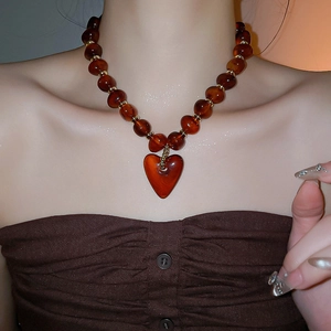 Macro shot of a vintage amber resin heart necklace with gold beads on a model