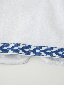 Close-up of intricate blue geometric embroidery on white fabric with fine texture detail