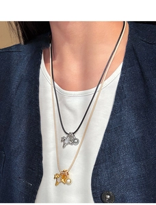 Détail de pendentifs chevaux superposés en or et argent sur des cordons tissés fins