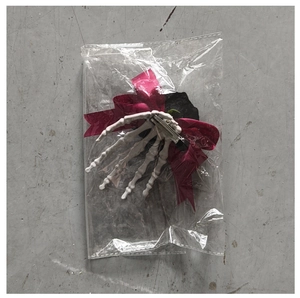 Détail d'une pince à cheveux main de squelette blanc avec nœud rouge et clip métallique