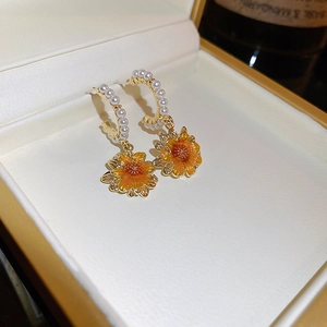 Detail of gold sunflowers earrings with pearls inside a jewelry box for women