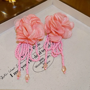 Detail of pink fabric flower earrings with beaded tassels and crystal charms