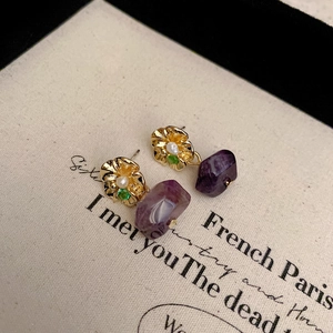 Detail of floral earrings with gold plating, pearls, and purple gemstones