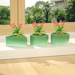 Drie groene geometrische bloempotten met verticale strepen op een zonnige vensterbank