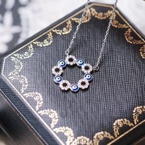 Vue macro du collier œil du démon en argent avec émail bleu et zircon sur un écrin à bijoux