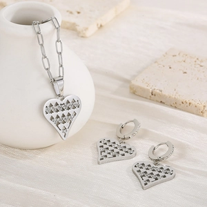 Silver hollow heart jewelry set with necklace and earrings on a silk background