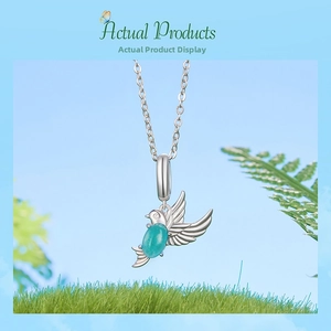 Detailed macro shot of 925 silver bird pendant with teal gemstone over green grass