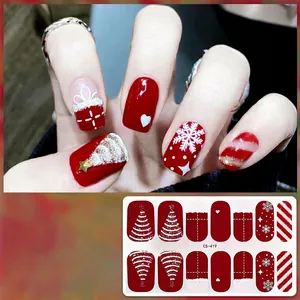 Detailed view of red Christmas gel nail stickers with gold glitter and snowflake patterns