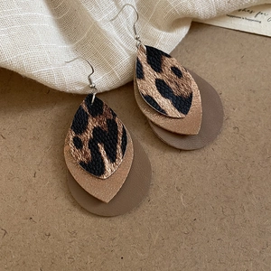 Close-up of three-layer leaf earrings with leopard print and gold glitter on paper