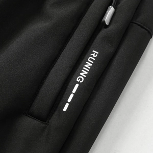 Detail einer schwarzen Fleecehose-Tasche mit 'RUNING' Druck und Metallreißverschluss