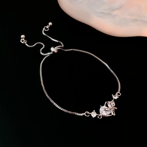 Detail of adjustable silver bow bracelet with heart pendants and sparkling zircons