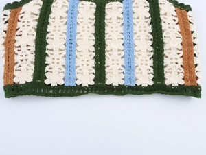 Detailed macro view of crochet knit vest with hollow flower patterns and color block stripes