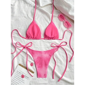 Flat lay of pink lace-up bikini set with sunglasses and floral beach accessories