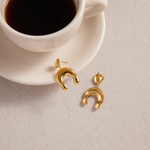 Boucles d'oreilles dorées en U avec texture métal liquide sur fond minimaliste