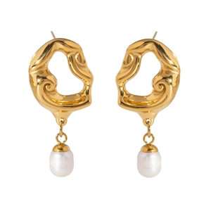 Détails macro de boucles d'oreilles évidées dorées avec perles blanches élégantes