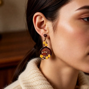 Close-up of vintage flower drop earring with amber resin and floral details on a model