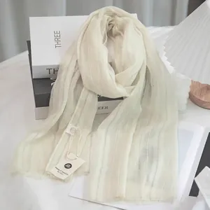 Detailed close-up of cream linen scarf with vertical stripes and natural frayed edges