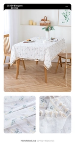 Detail of linen tablecloth with blue daisy pattern and decorative cream tassel fringe