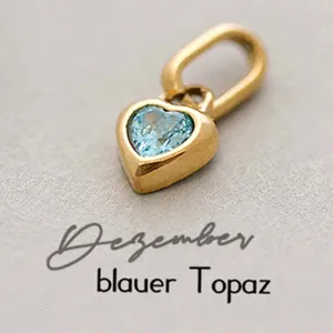 Macro detail of heart pendant in gold finish with December blue topaz gemstone