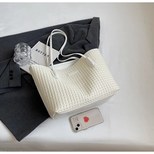 Detail of cream woven tote bag texture with slim straps on a casual lifestyle background