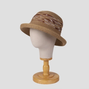 Détail d'un chapeau de paille tissé avec un ruban décoratif à motifs géométriques marron