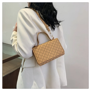 Rear view of a model wearing a brown printed crossbody bag with a white blazer