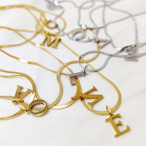 Macro detail of gold and silver letter pendants on flat snake bone necklaces